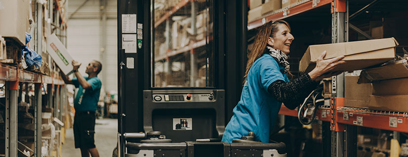 Imagem de uma mulher e um homem dentro de um depósito mexendo nas mercadorias nas prateleiras